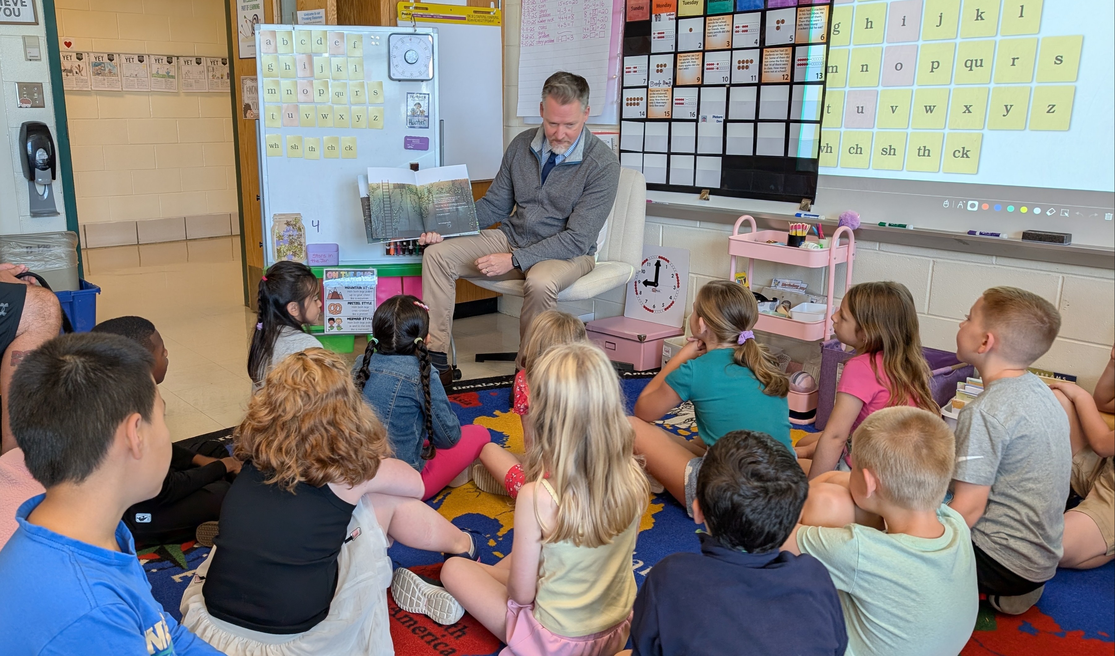 Students sit and listen as Principal Blanchard reads them a book.