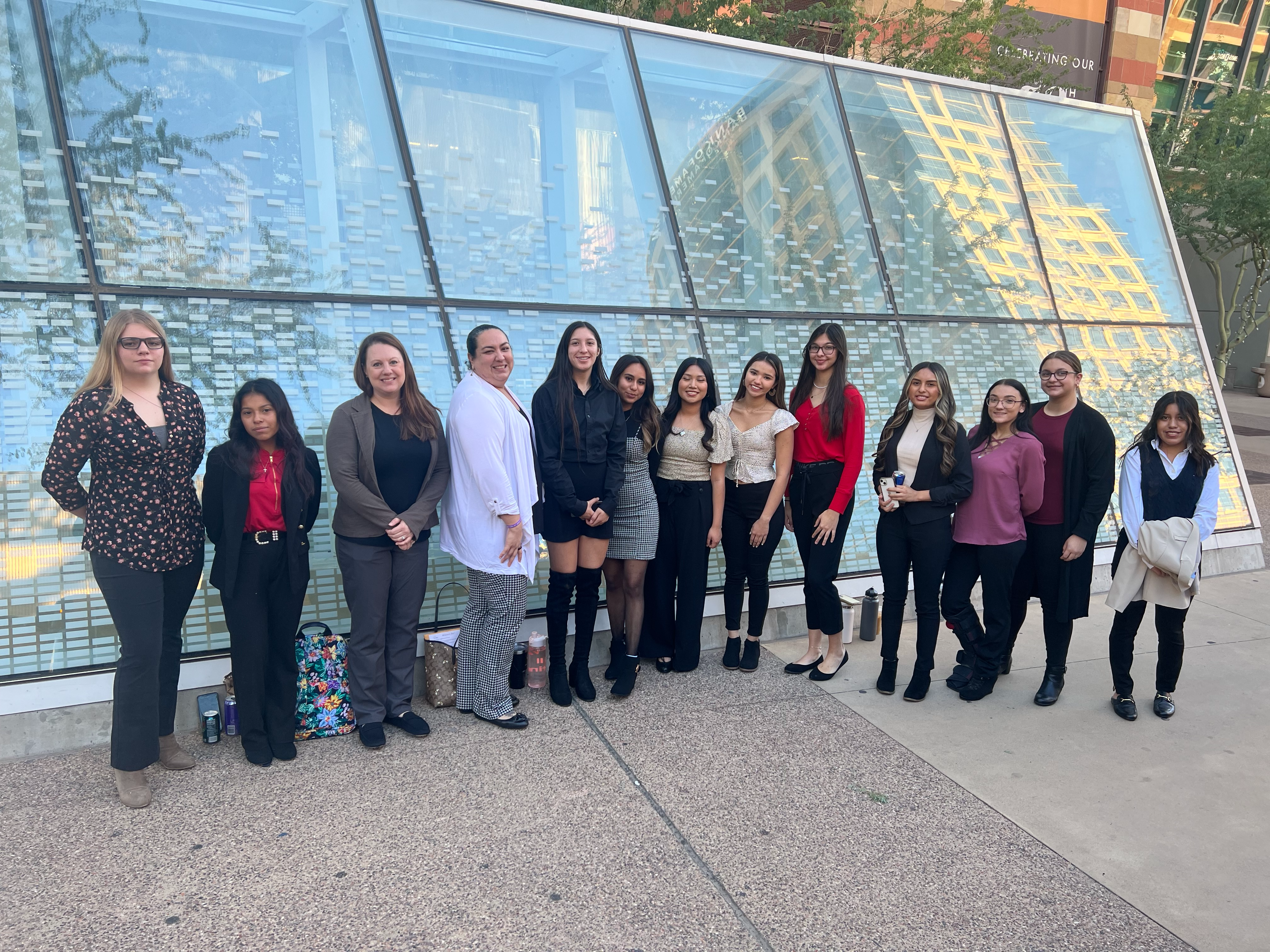 group of students standing in front of glass window in professional dress