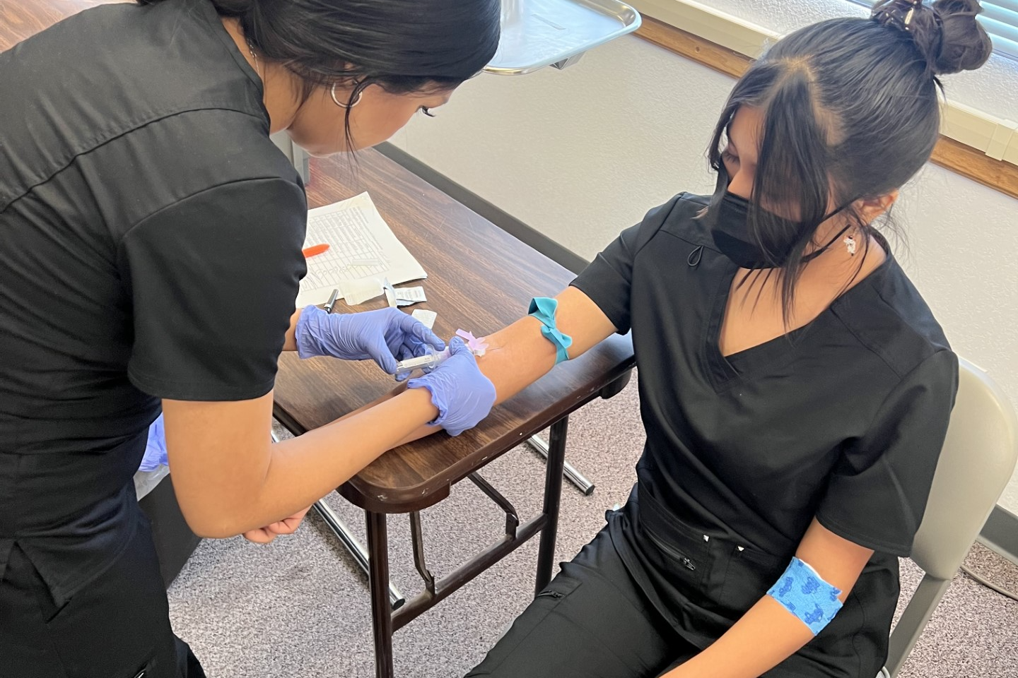 Student practicing blood draw on mannequin