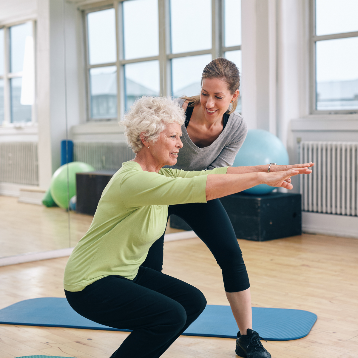 personal trainer with senior female doing squats