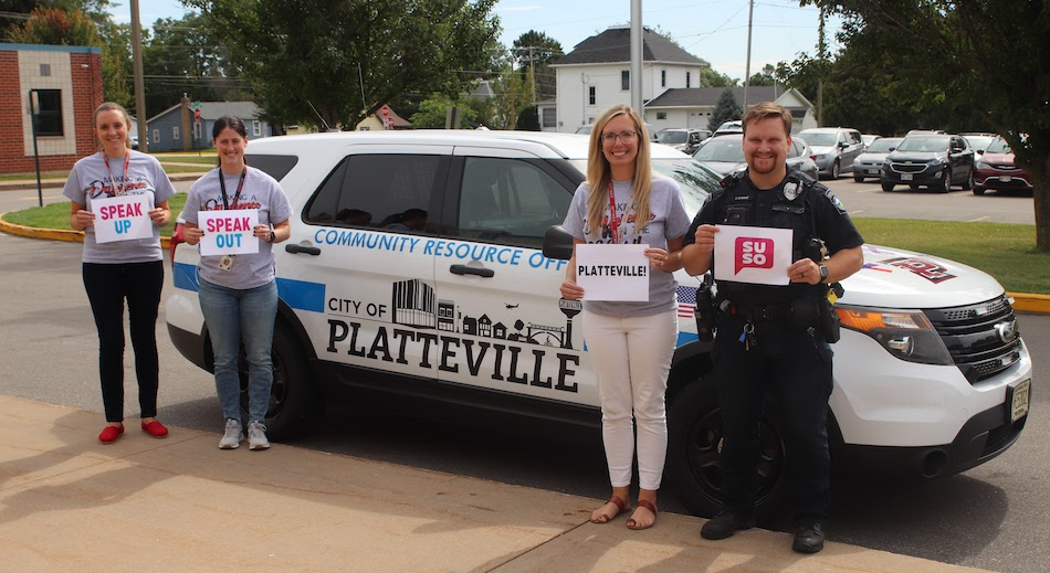 Staff members holding signs in front of a "City of Platteville" vehicle