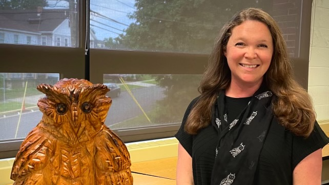 Kristina Donavan smiling next to a statue of an owl