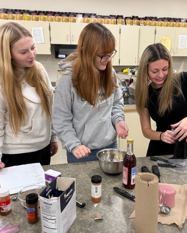 Three students cook in a kitchen