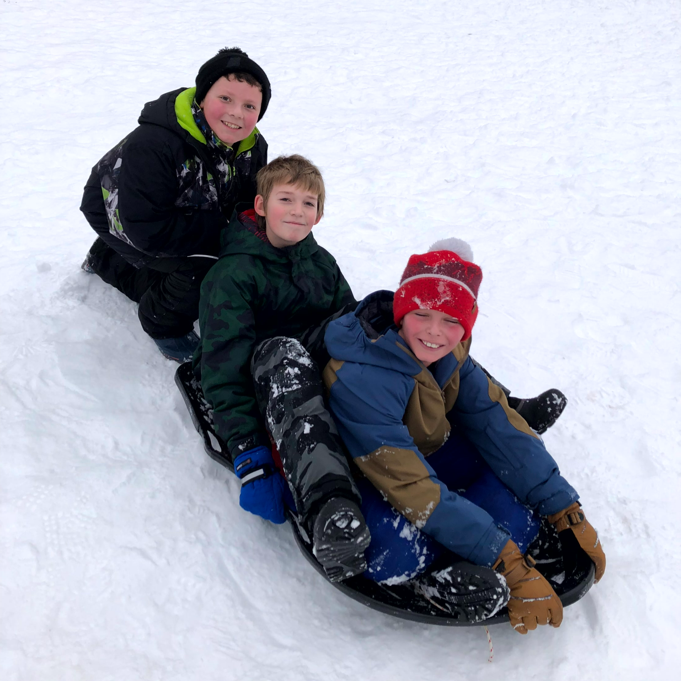 Three students sit on a sled