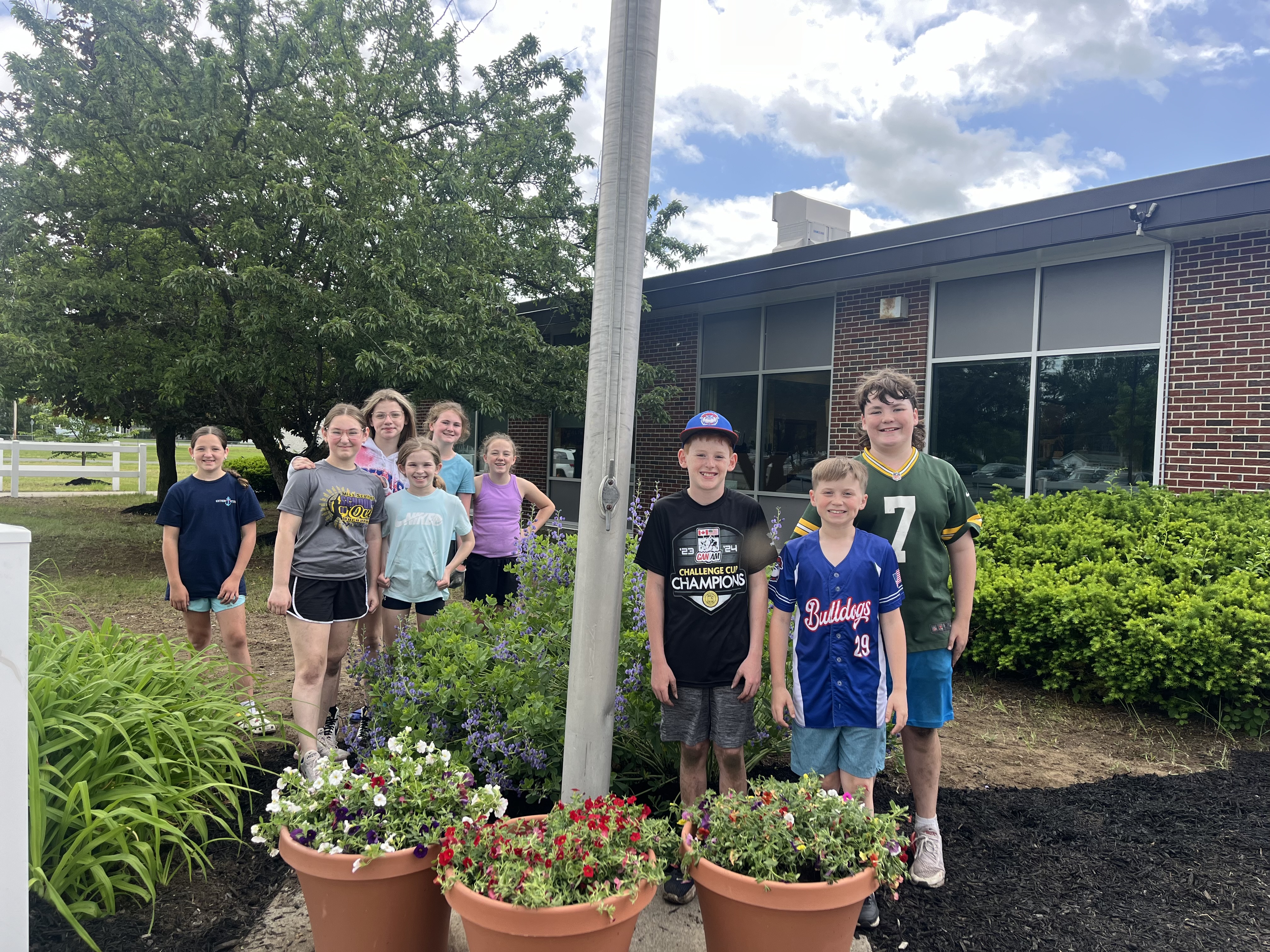 Student council members pose in front of the flag pole
