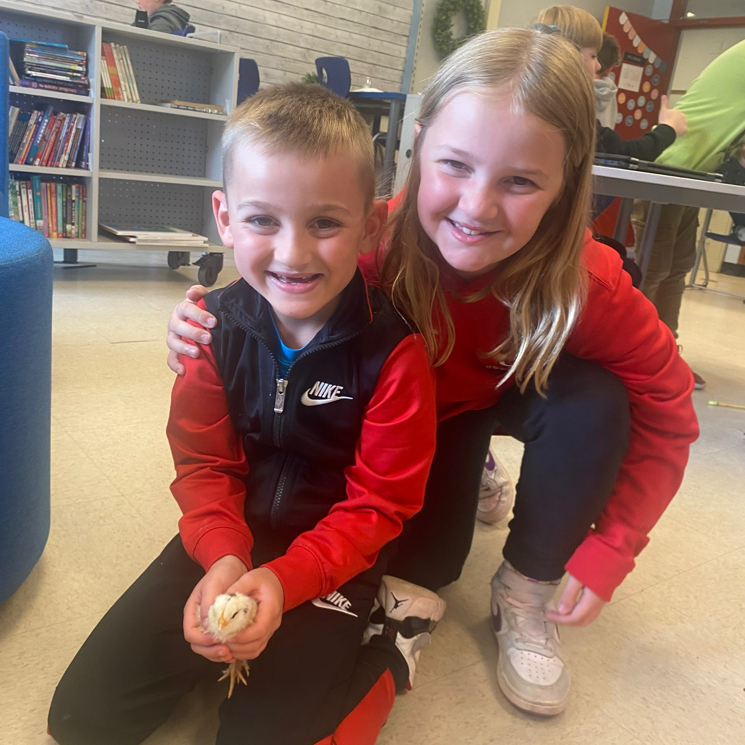 Two students show a newly hatched baby chicken