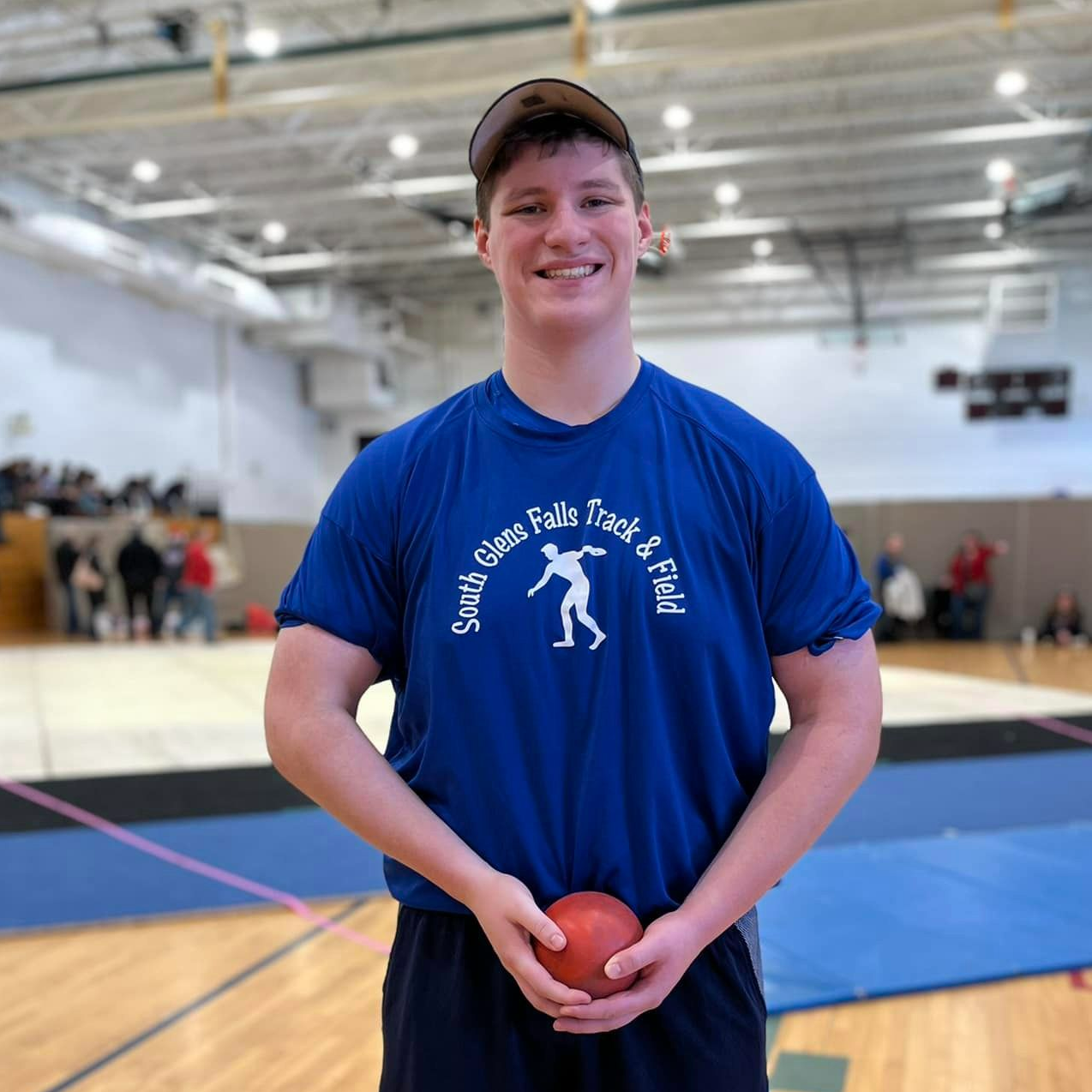 Nick Wright stands holding a shot put 