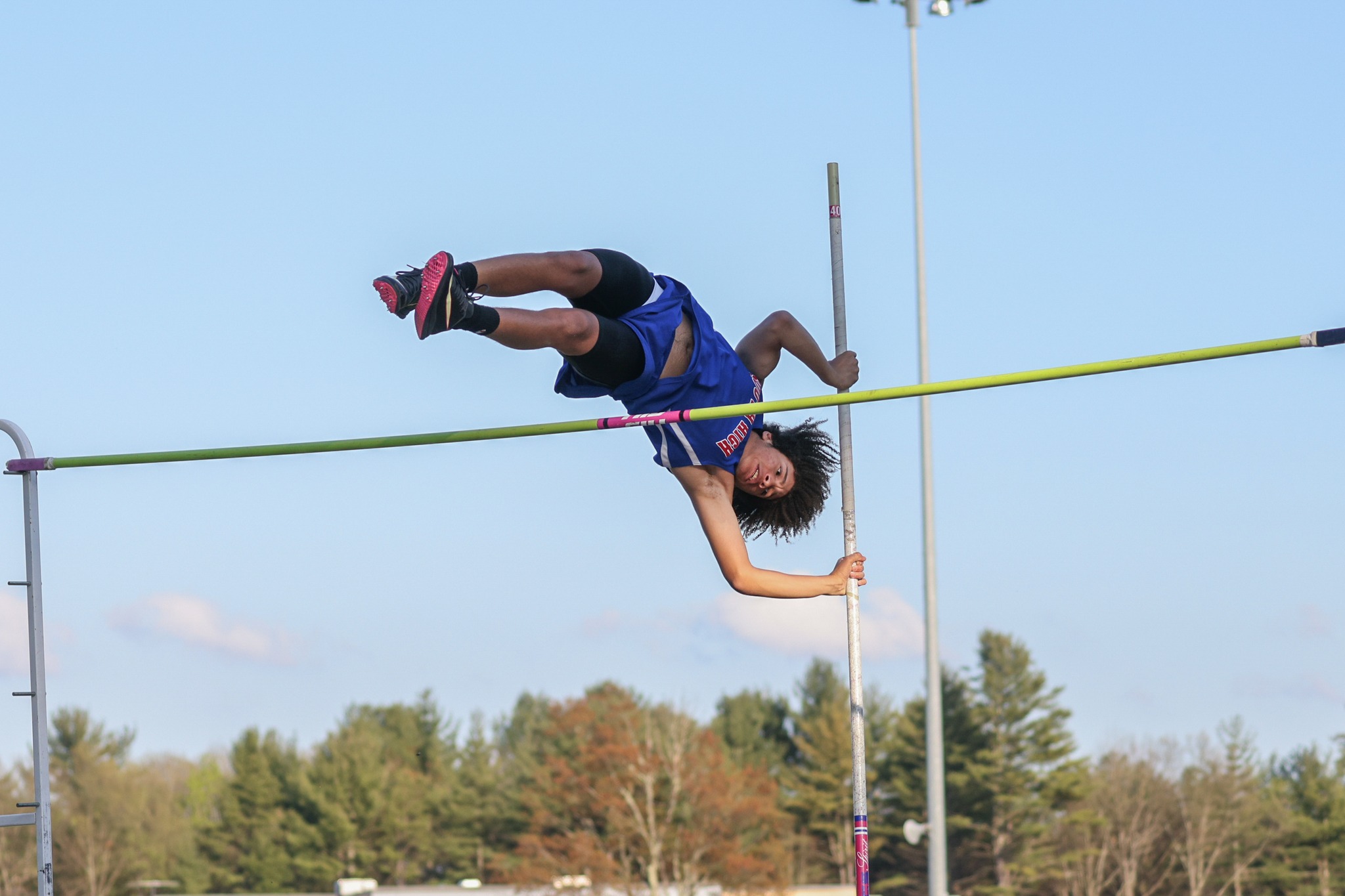 A student jumps over a pole during a high jump competition