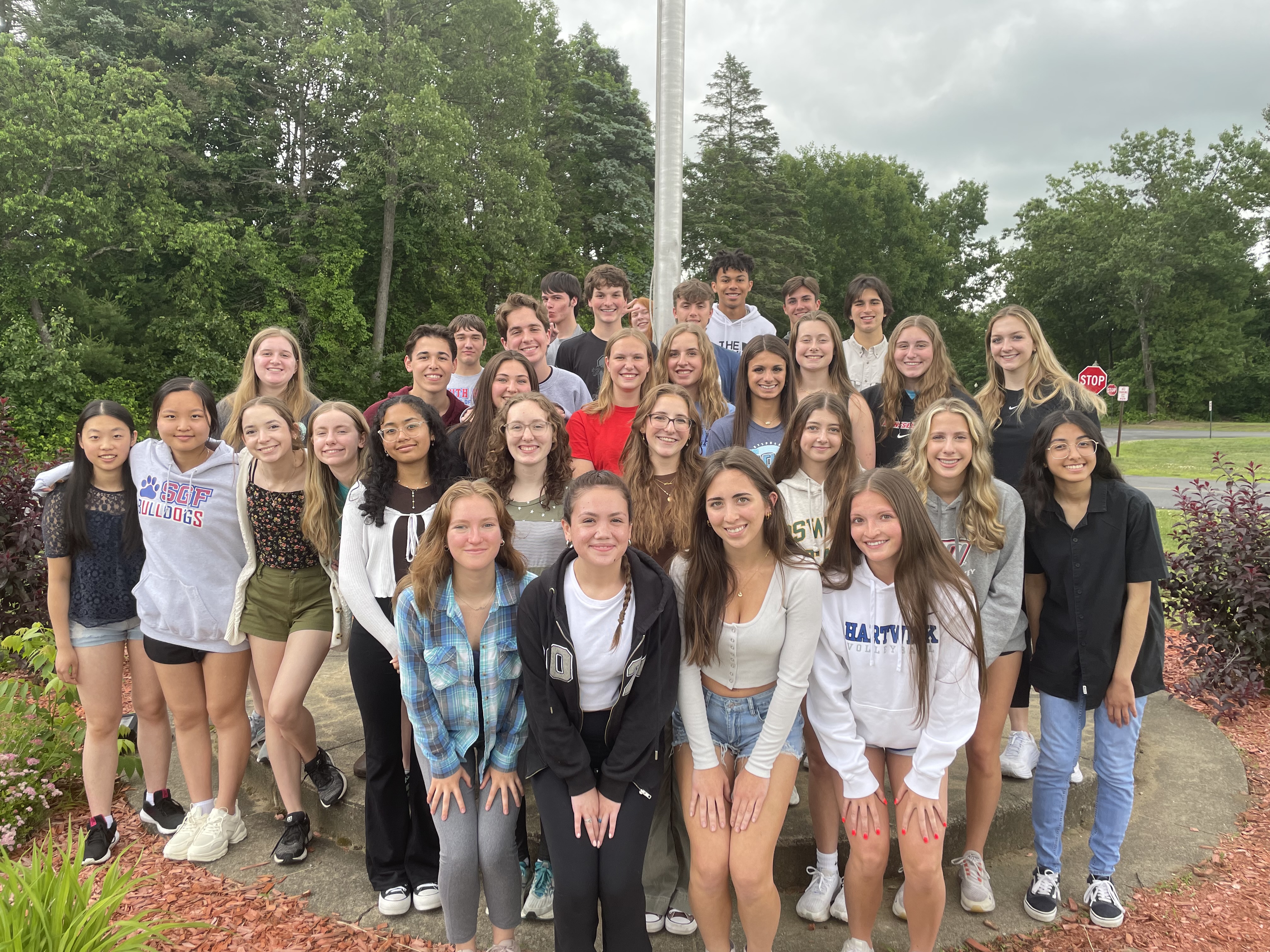 Students pose in front of a flag pole