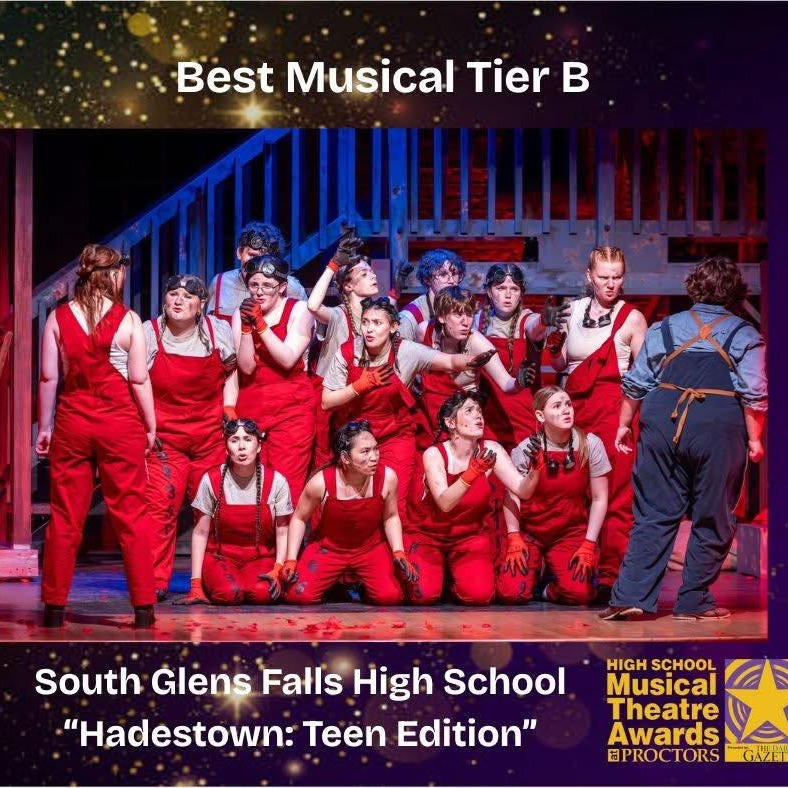 Group of performers in red overalls on stage during a scene from 'Hadestown: Teen Edition.' Text at the top reads 'Best Musical Tier B.' Bottom text states 'South Glens Falls High School Hadestown: Teen Edition' with the High School Musical Theatre Awards at Proctors logo.