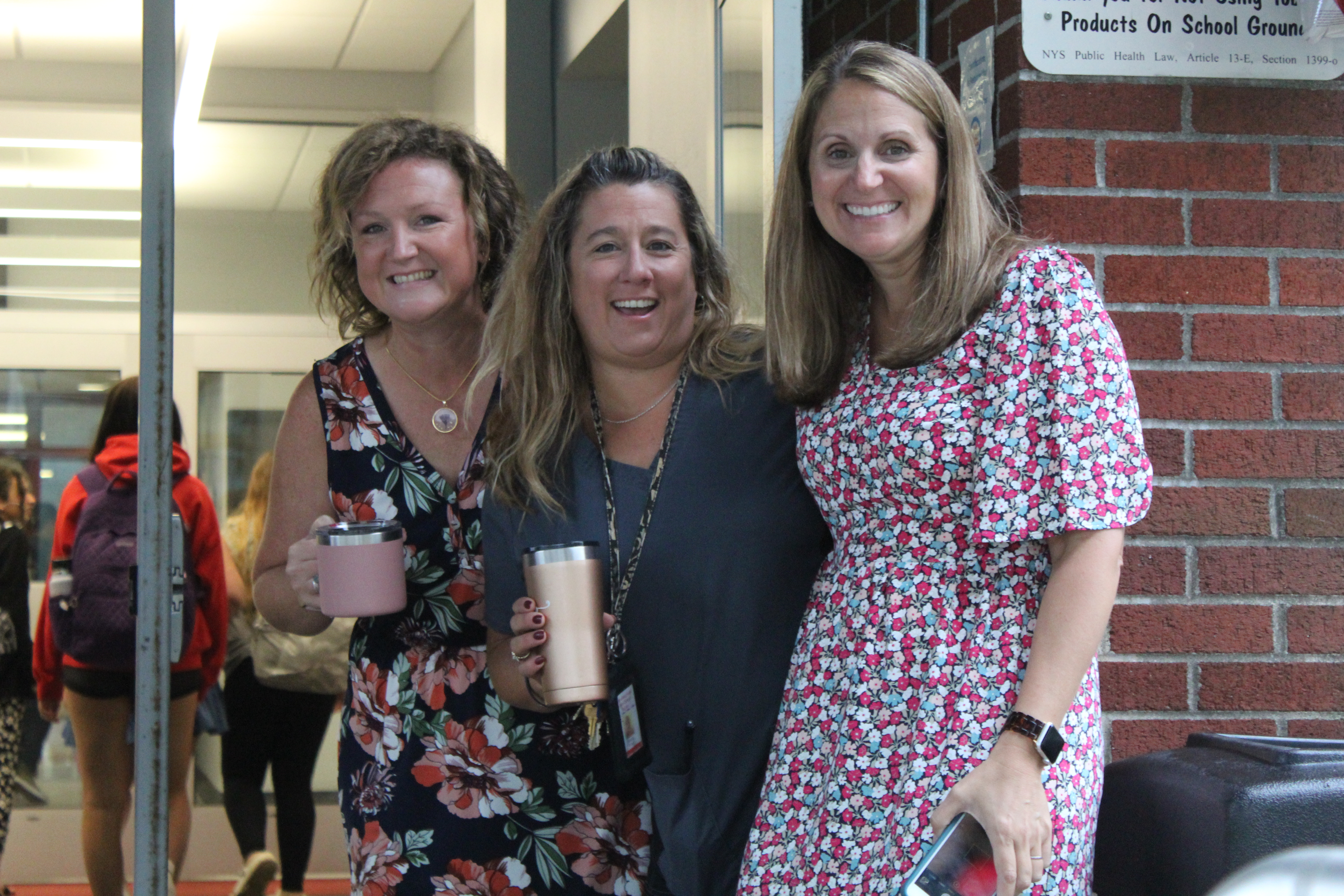 Three staff members pose near the front door of South High