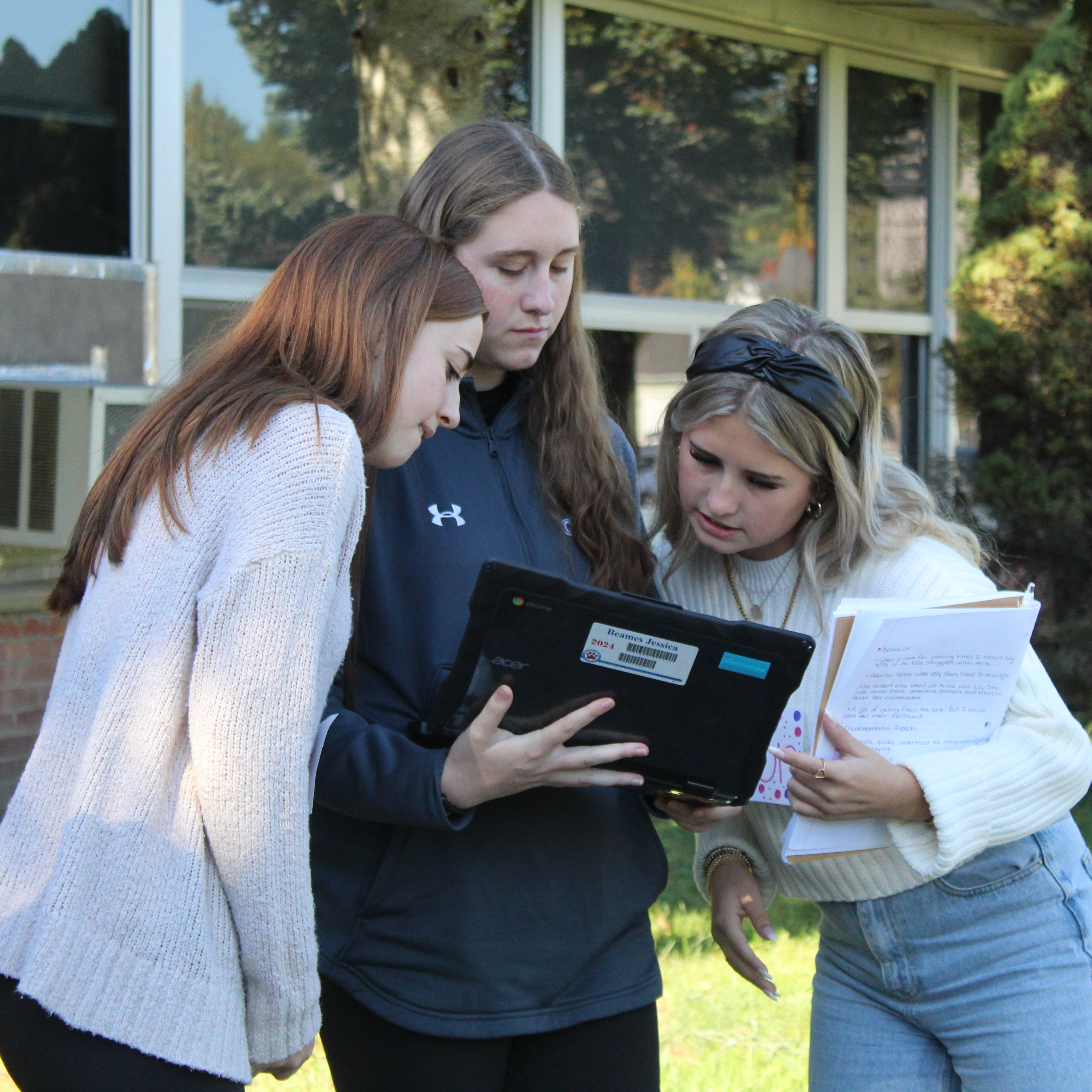 Three students look at a tablet