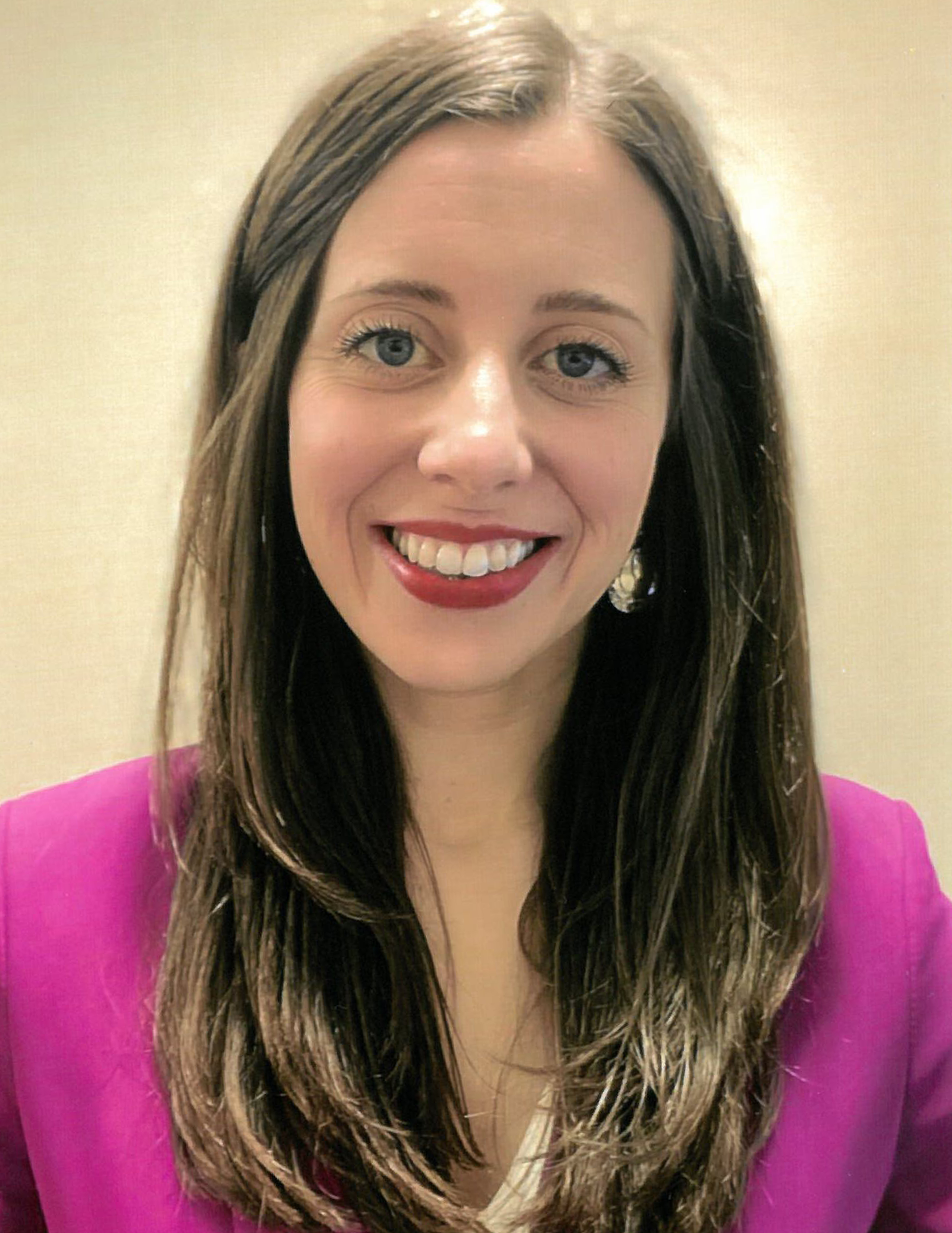 Stands wearing a purple shirt against a beige wall