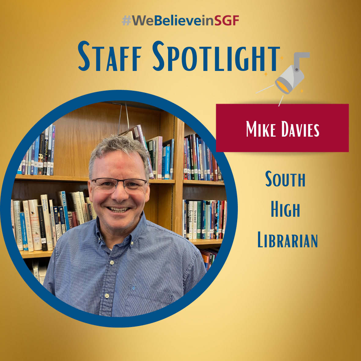 Mike Davies stands next to a shelf filled with books