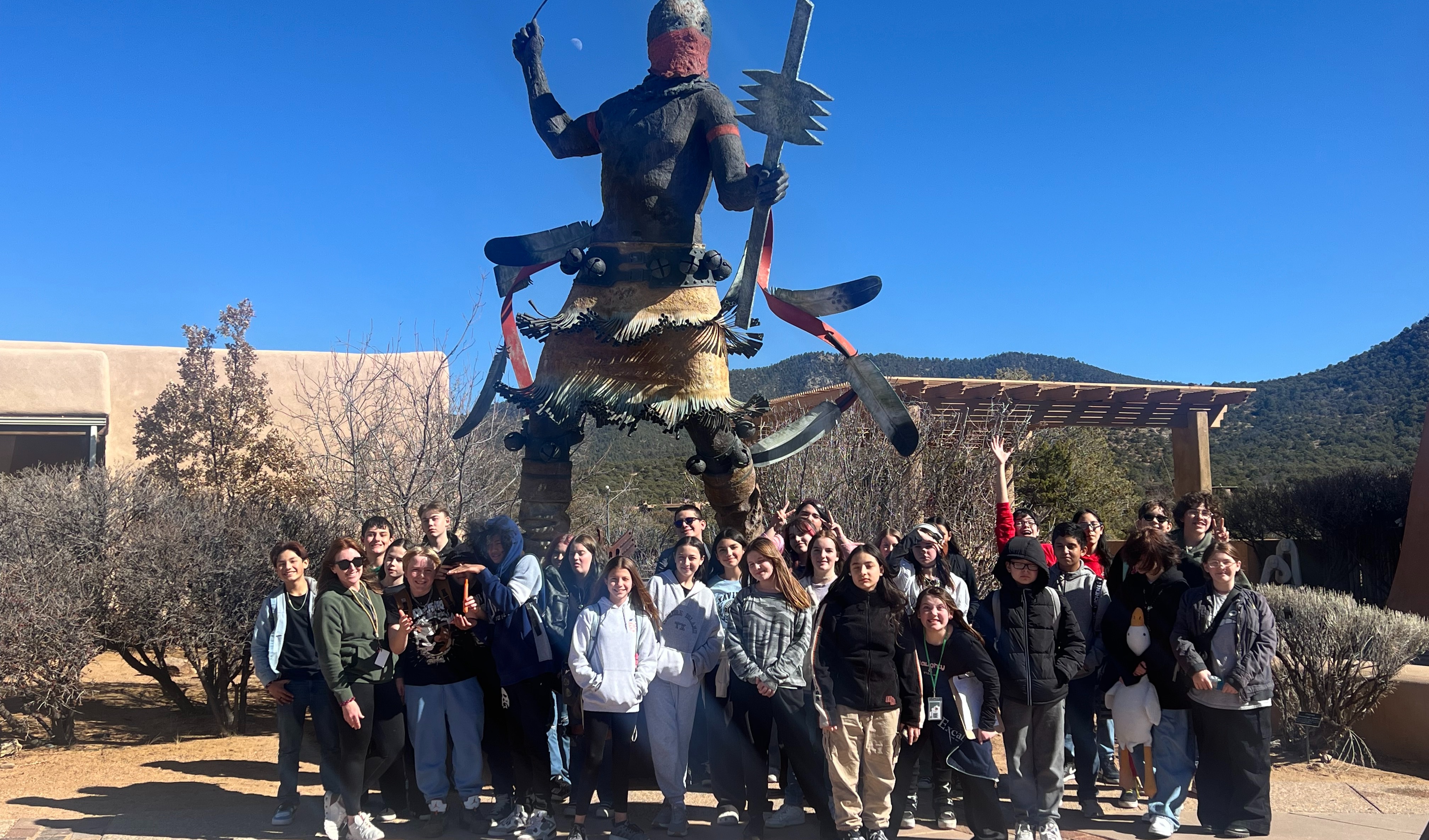 Middle school students posing in front of native american statuecream pie at the Field Trip day celebration.