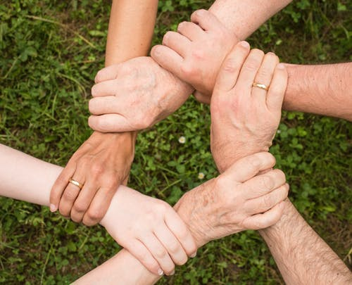 A photo with several hands holding each other forming a circle.