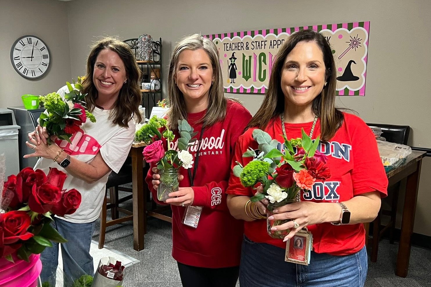 three female teachers holding flowers and vases