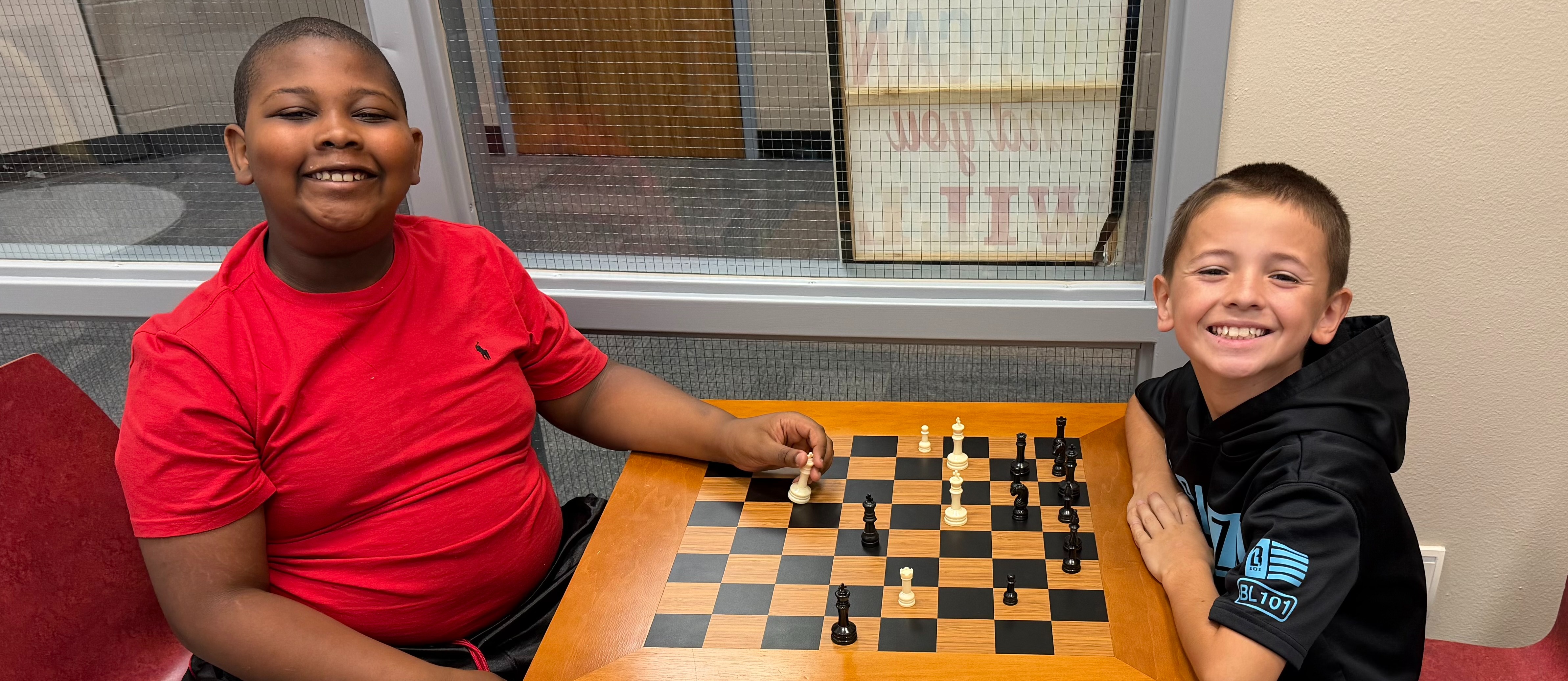 boy in red shirt and boy in black shirt playing chess