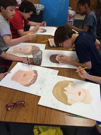 students drawing faces on pieces of paper