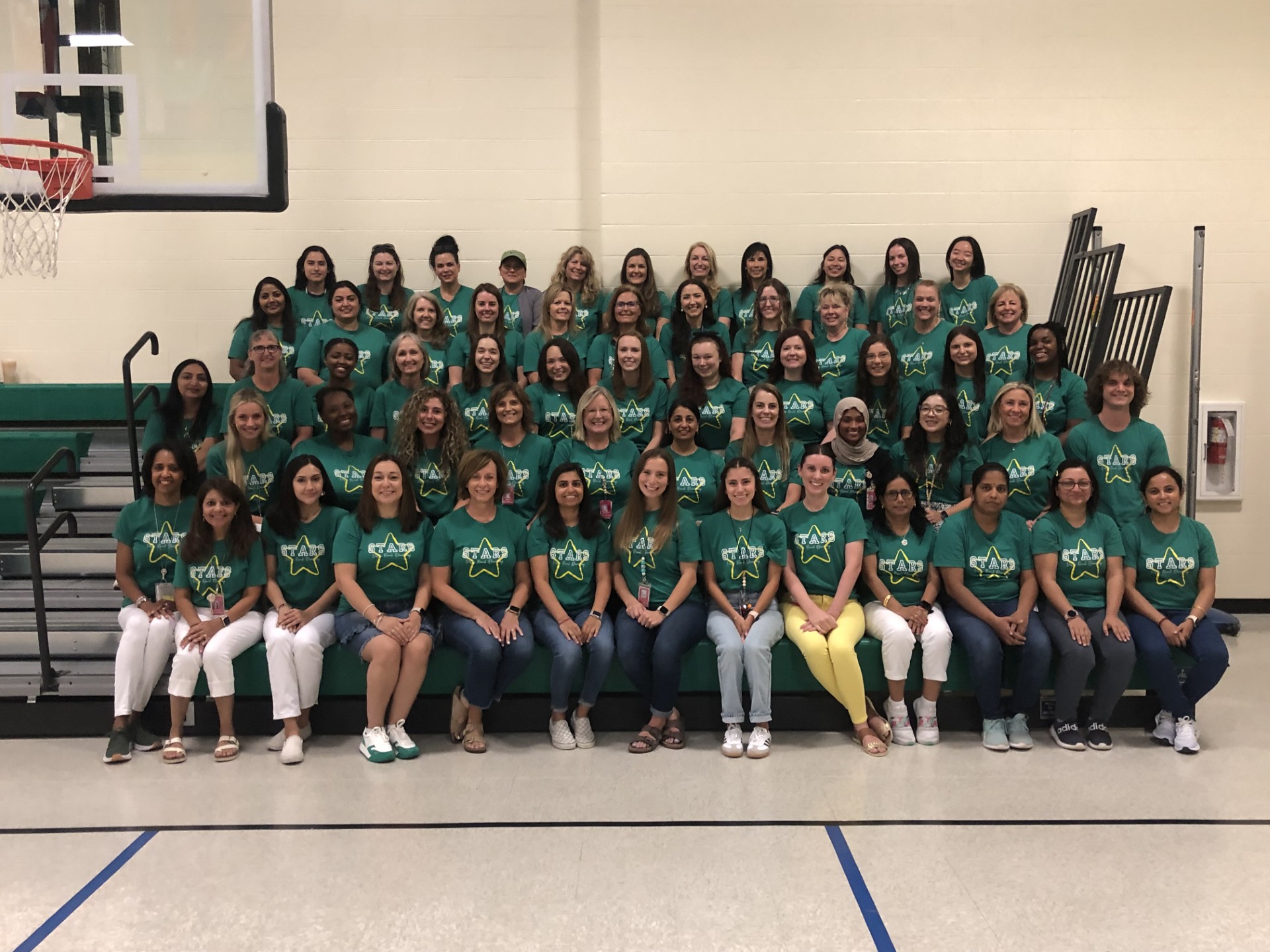 Photo of all VRE staff wearing green shirts sitting on bleachers