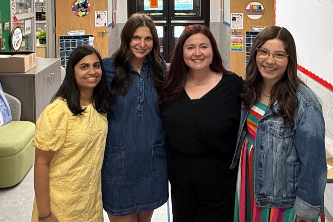 Group of four smiling kindergarten teachers standing in the school hallway.