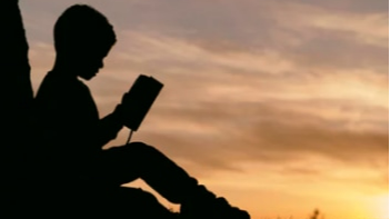 Student reading book overlooking sunset