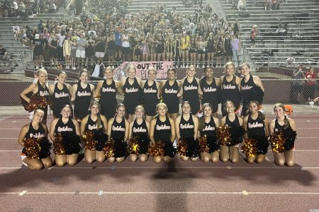 Cheer team stays cool on a hot football night during fall 2022.