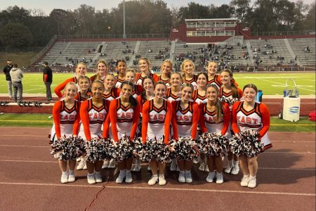 Cheer team poses on the sidelines during a football game fall 2022.