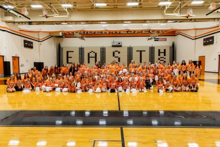 Cheer team poses with students at the end of a cheer clinic.