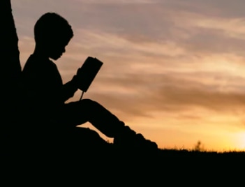 Student reading book over sunset