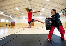 Student jump kicking a punching bag