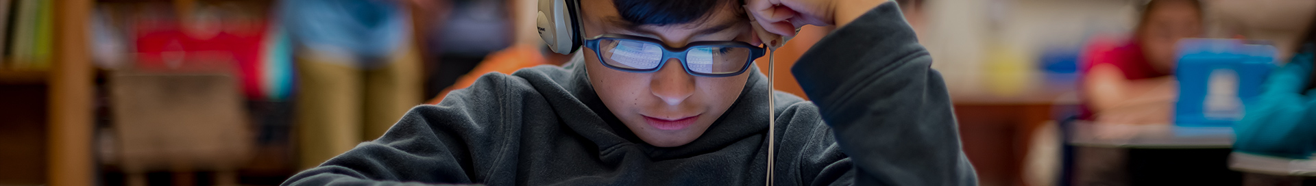 A student looking down at a device with headphones