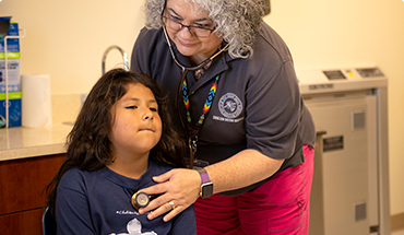 A nurse listening to a student's heartbeat