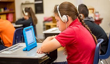 A student watching a tablet with headphones on