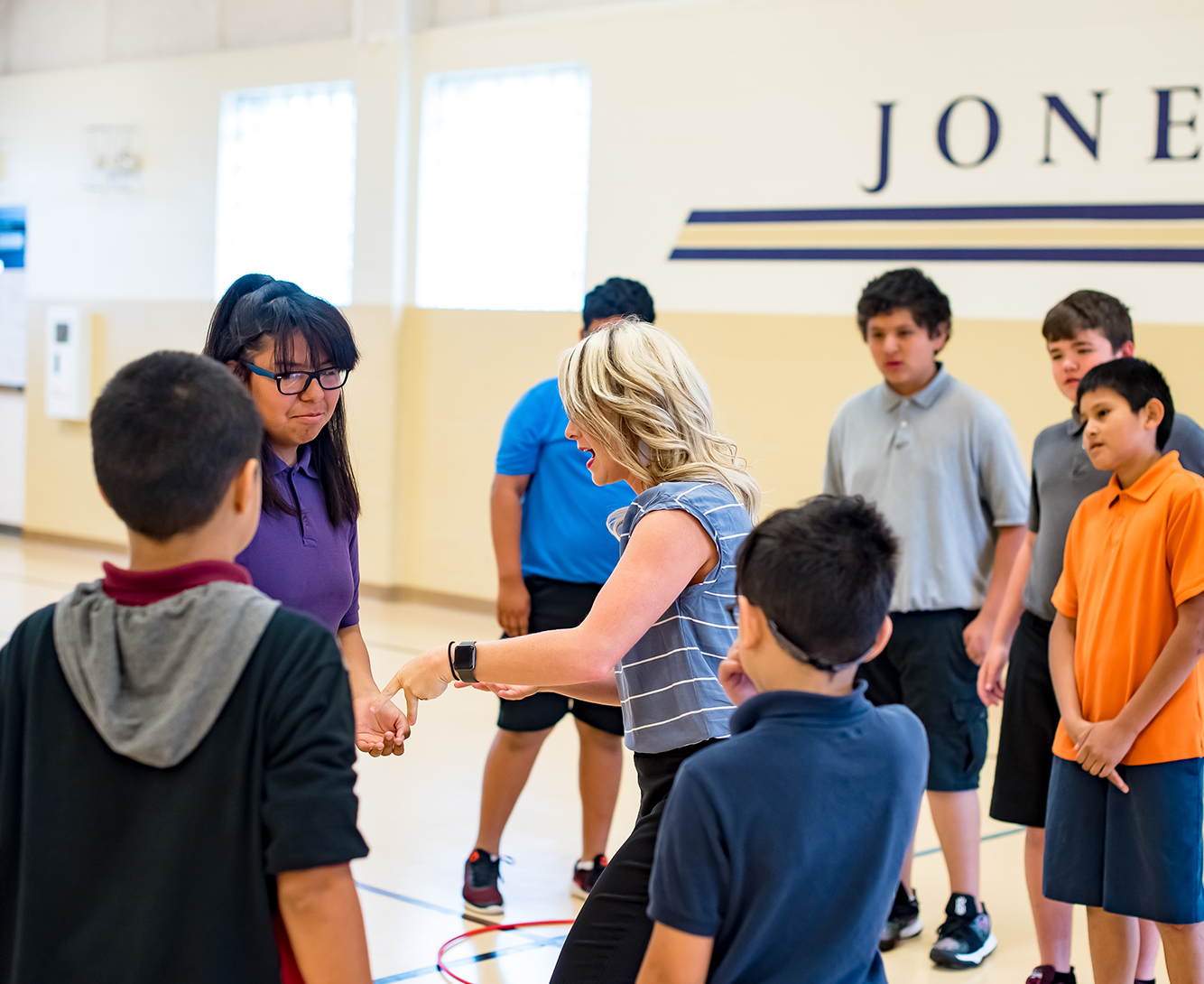 A PE teacher instructing students in the gym