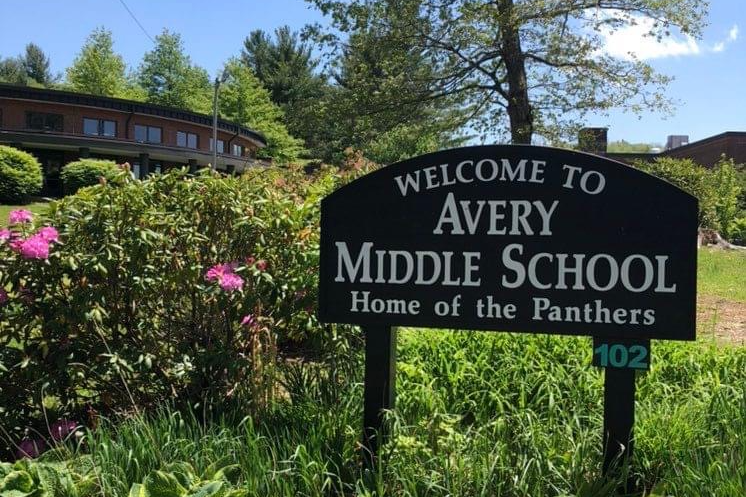 School sign located in an outdoor flower garden on a sunny day.