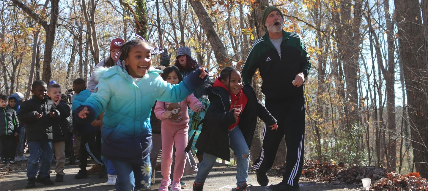 Elementary school students run across the starting line of a footrace in a local park during the fall