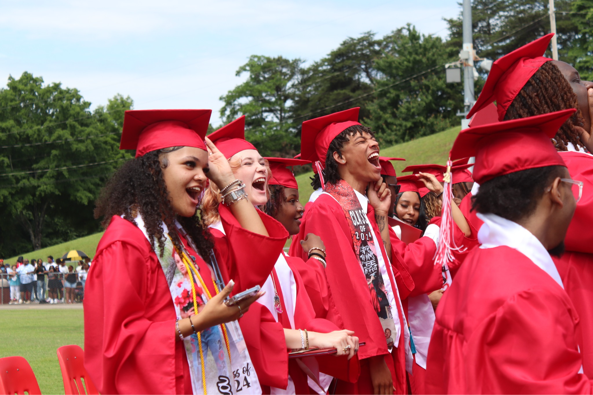 Students in red graduation robes cheer