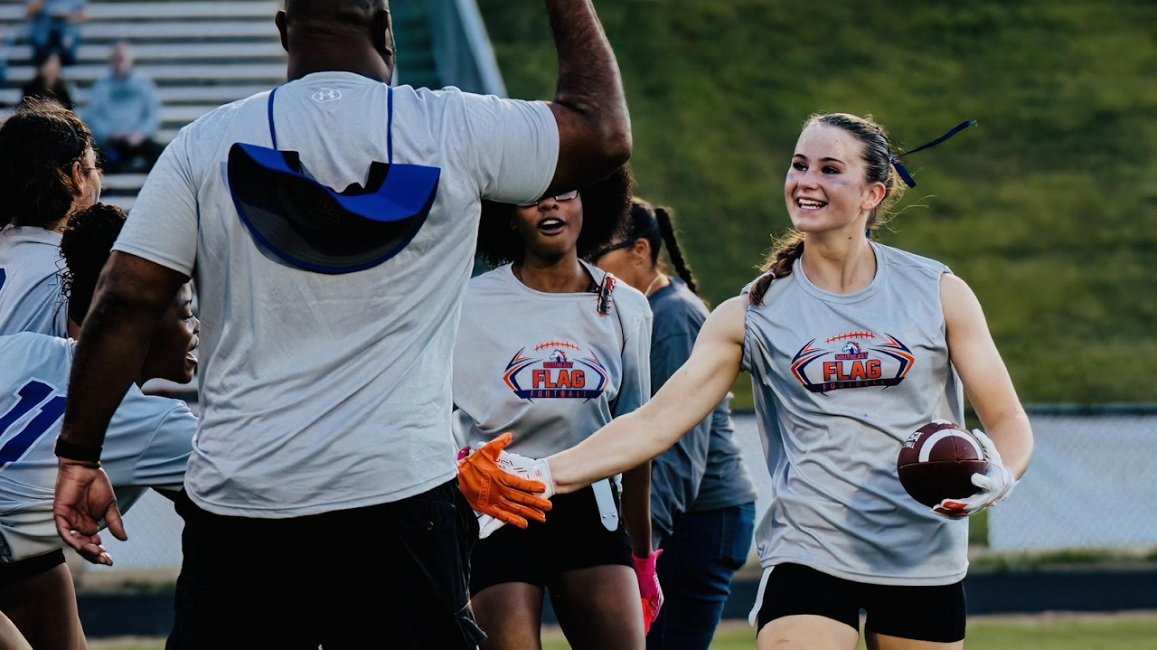 flag football player getting high fives from her coach and teammates