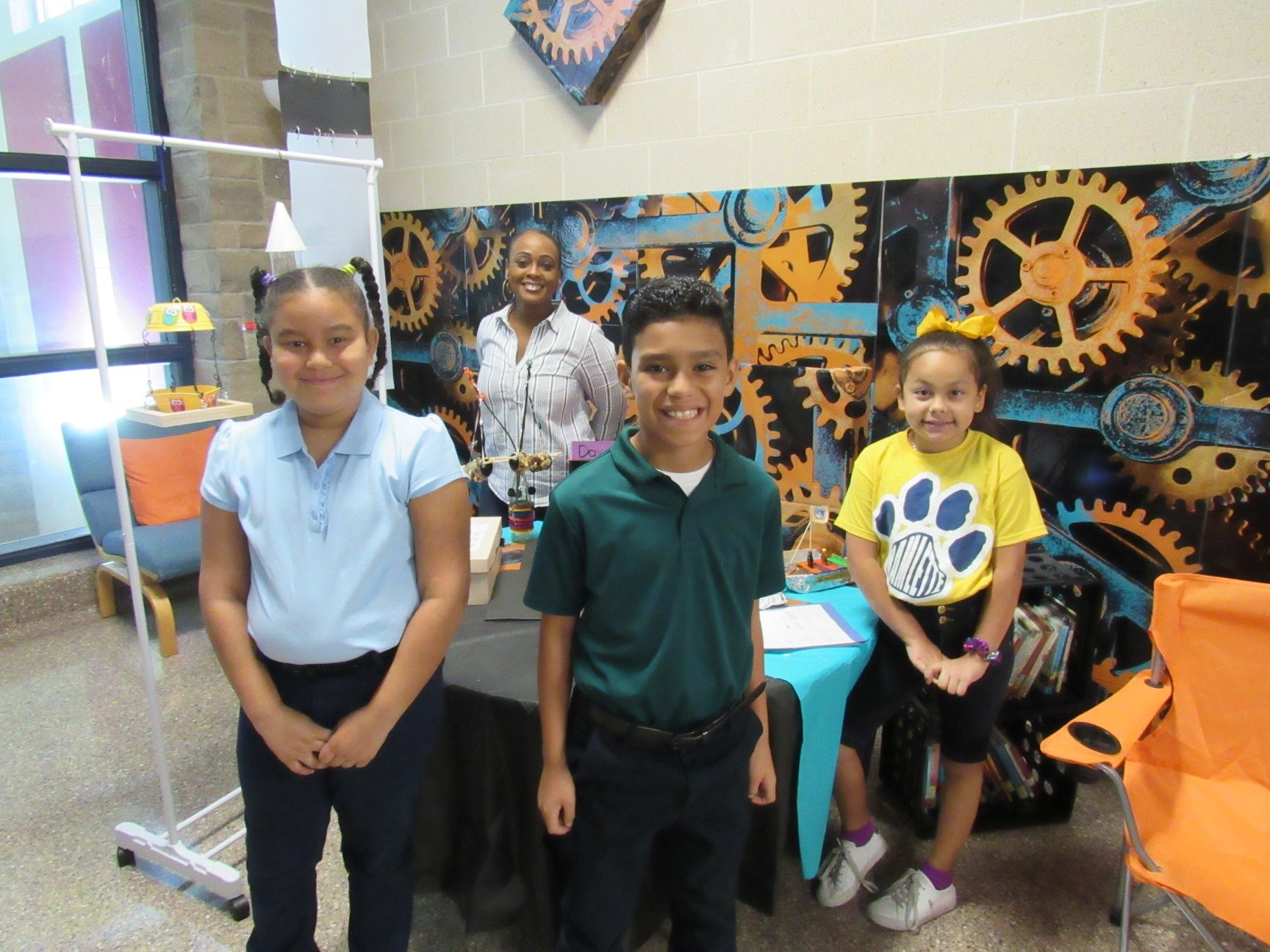 students posing in front of gear wall