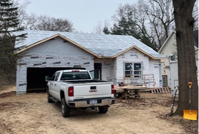 The student-build house with a white pickup truck out front. House is not roofed or sided.