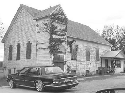 black and white image of large home with car parked in front