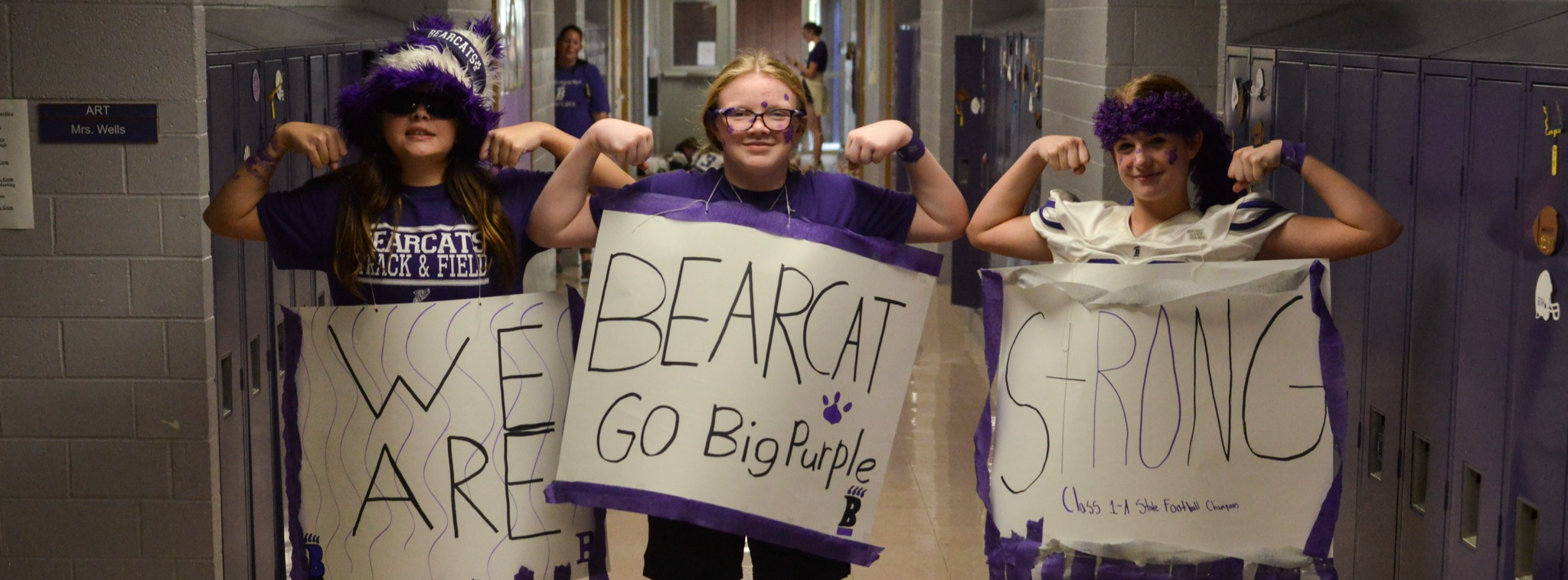 Homecoming week 3 kids with signs that say Bearcat Strong 