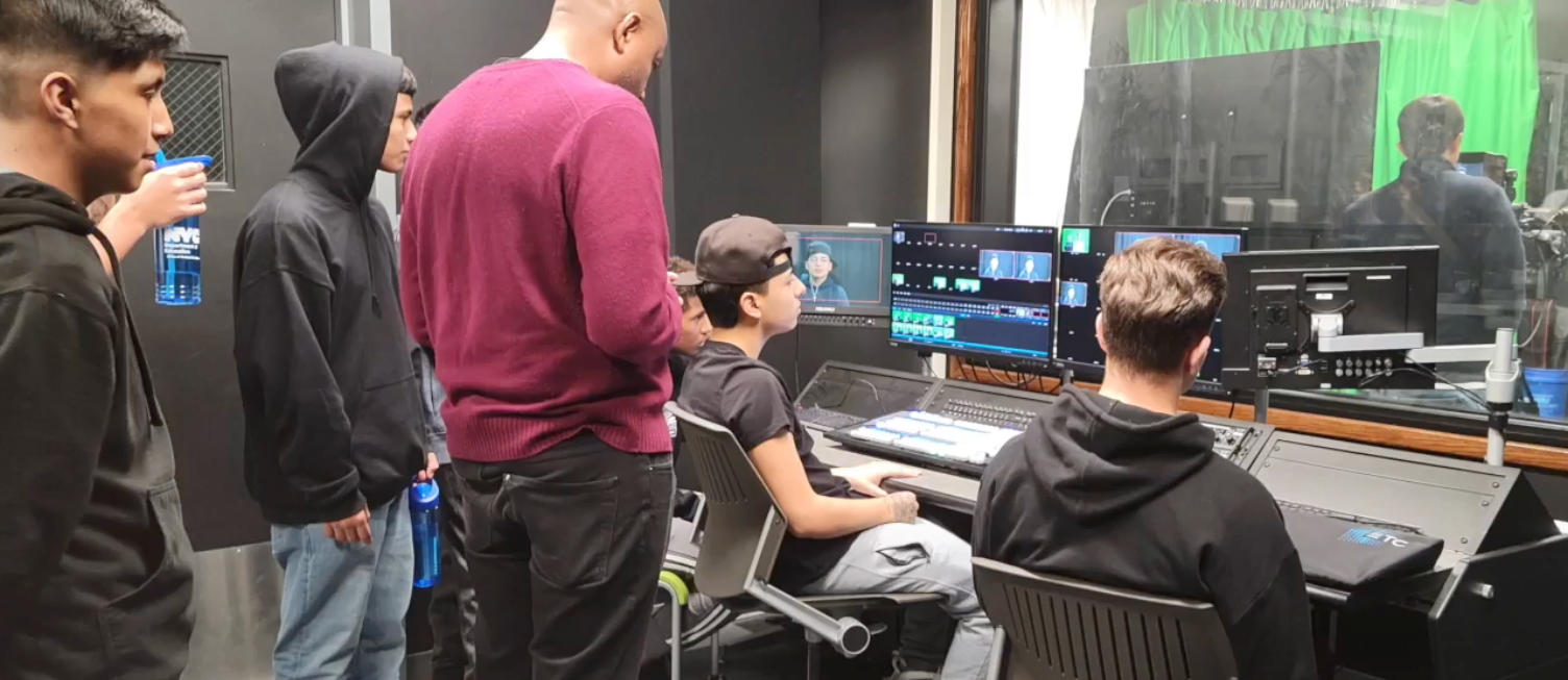 A film teacher is guiding students on using the live production equipment.