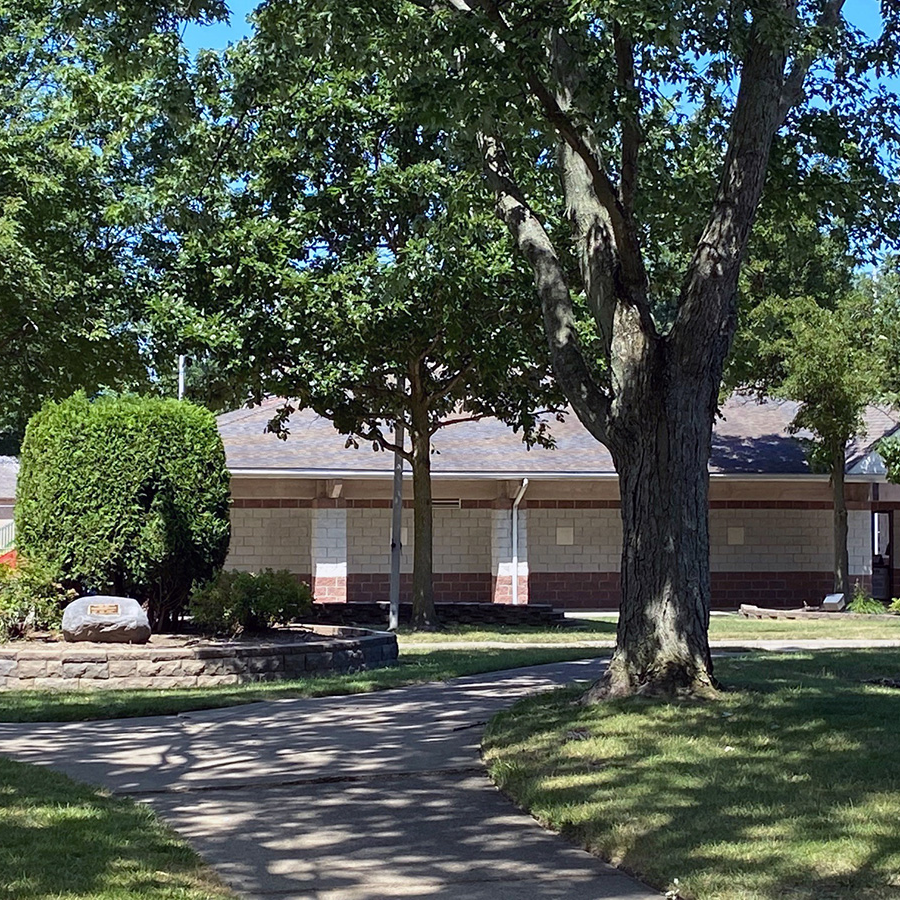 spray park brick building with large tree and sidewalk