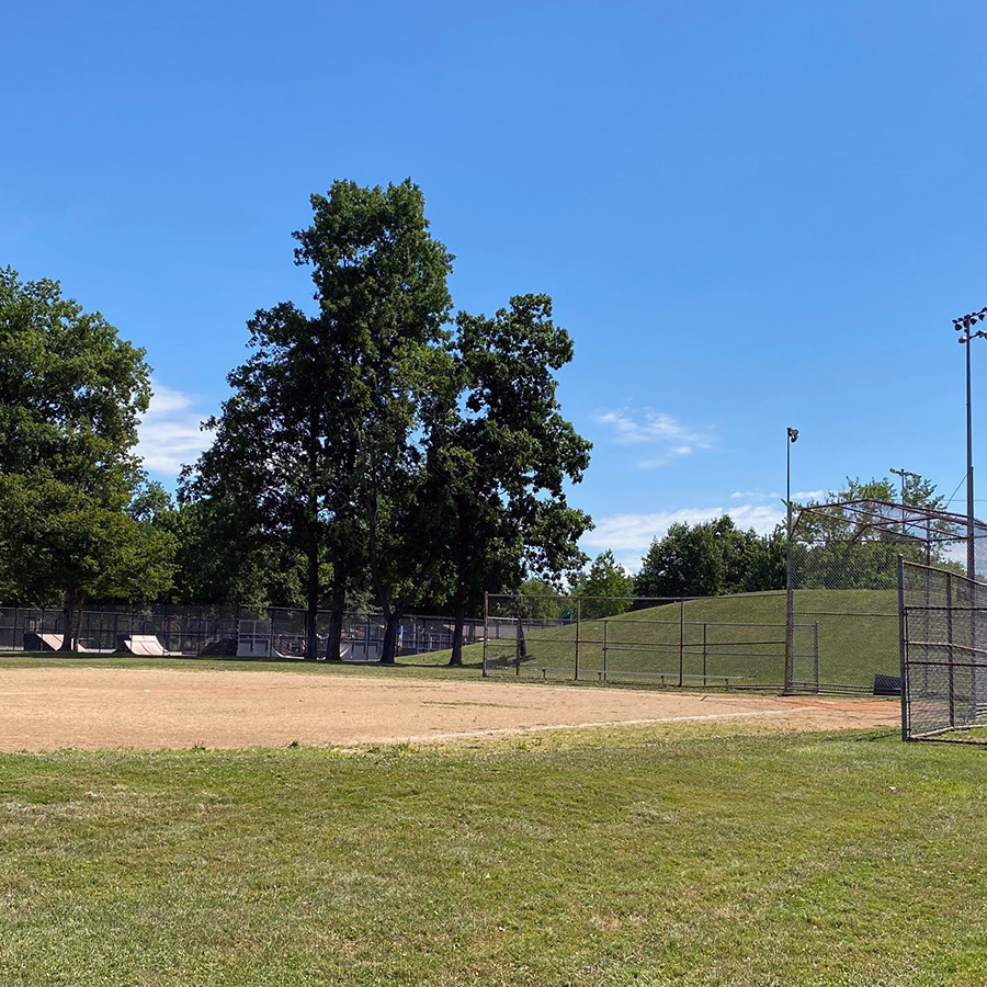 baseball field with trees and light poles