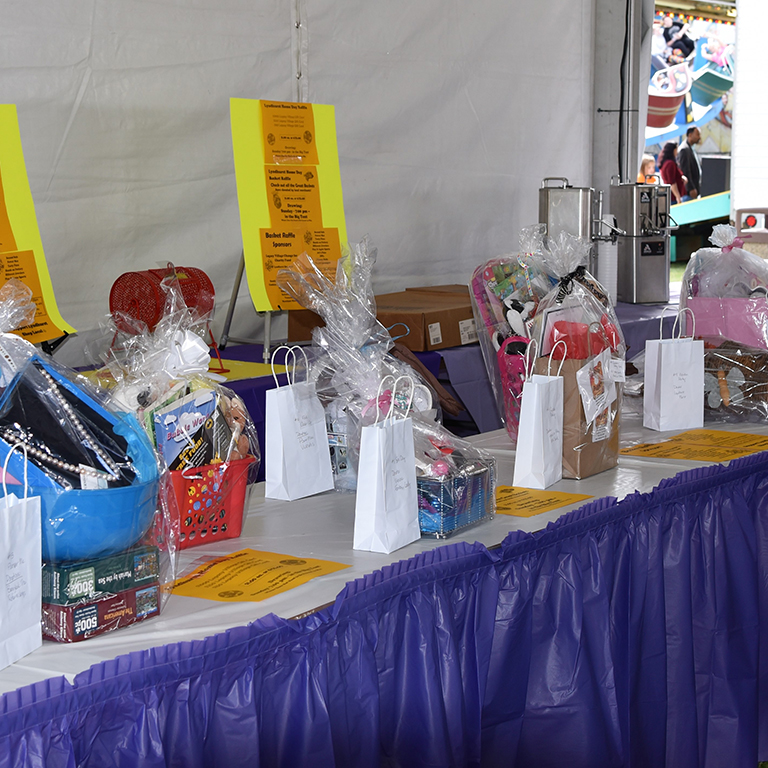 Raffle baskets on table with purple skirt and yellow signs