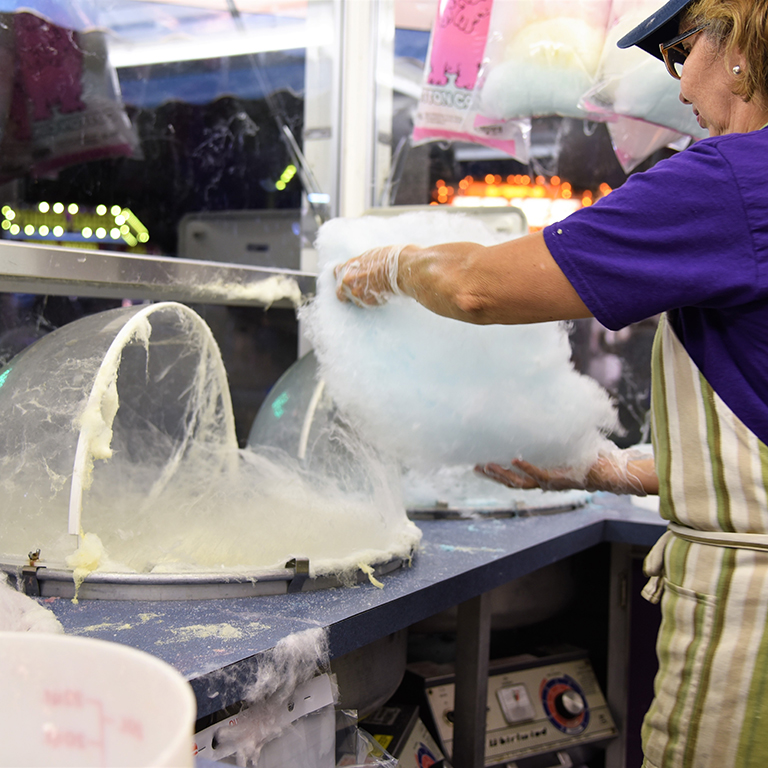 Lady wearing purple shirt making cotton candy