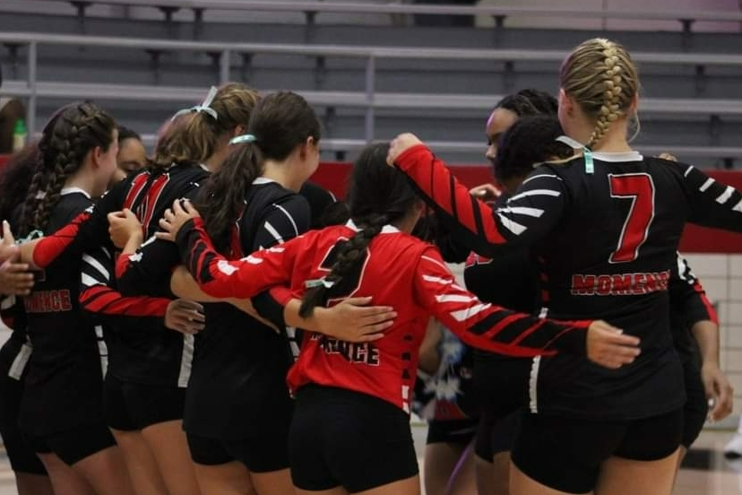 Momence High School Volleyball team in a huddle.