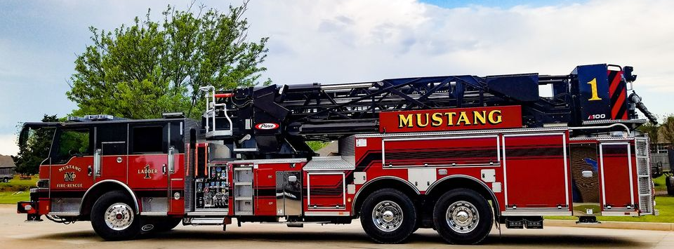 Firetruck with blue skies and large tree in background